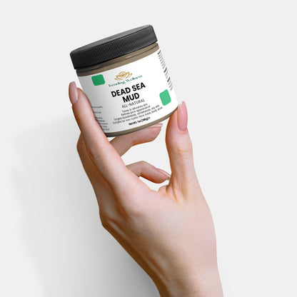 Hand holding a jar of Dead Sea Pure Mud on a white background