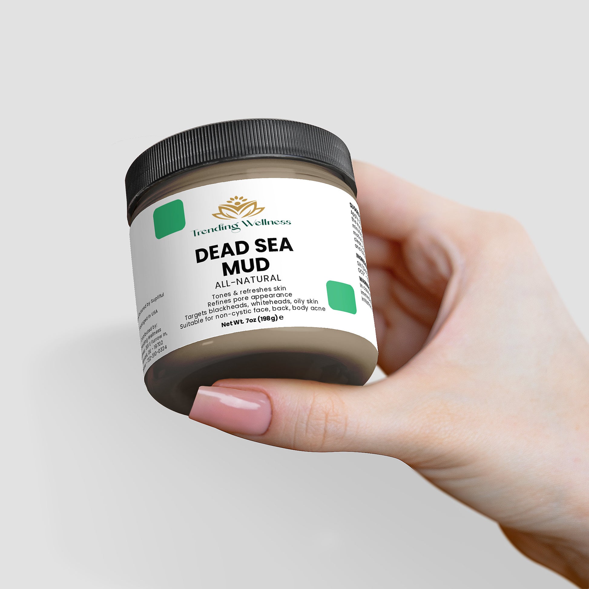 Hand holding a jar of Dead Sea Mud with a white background