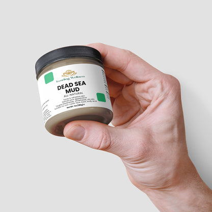 Hand holding a jar of Dead Sea Mud against a light gray background
