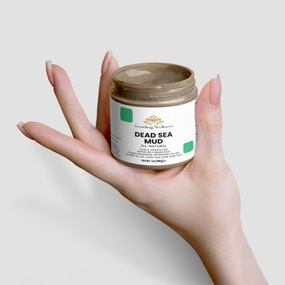 Hand holding a jar of Dead Sea Mud with a plain background